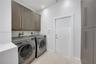 Laundry space featuring wood-finish cabinetry, floor-to-ceiling storage, wood-finish flooring, and recessed lighting