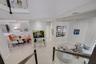 Open-concept living space featuring high ceilings, neutral-toned flooring, glass panel stair railing, and recessed lighting