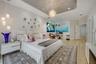 Tray ceiling featuring recessed lighting and a central decorative pendant, accompanied by wood-finish flooring and modern multi-light wall fixtures