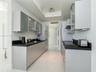 Contemporary kitchen featuring flat-panel cabinetry, frosted glass-front upper cabinets, contrasting dark countertops, integrated stainless steel appl