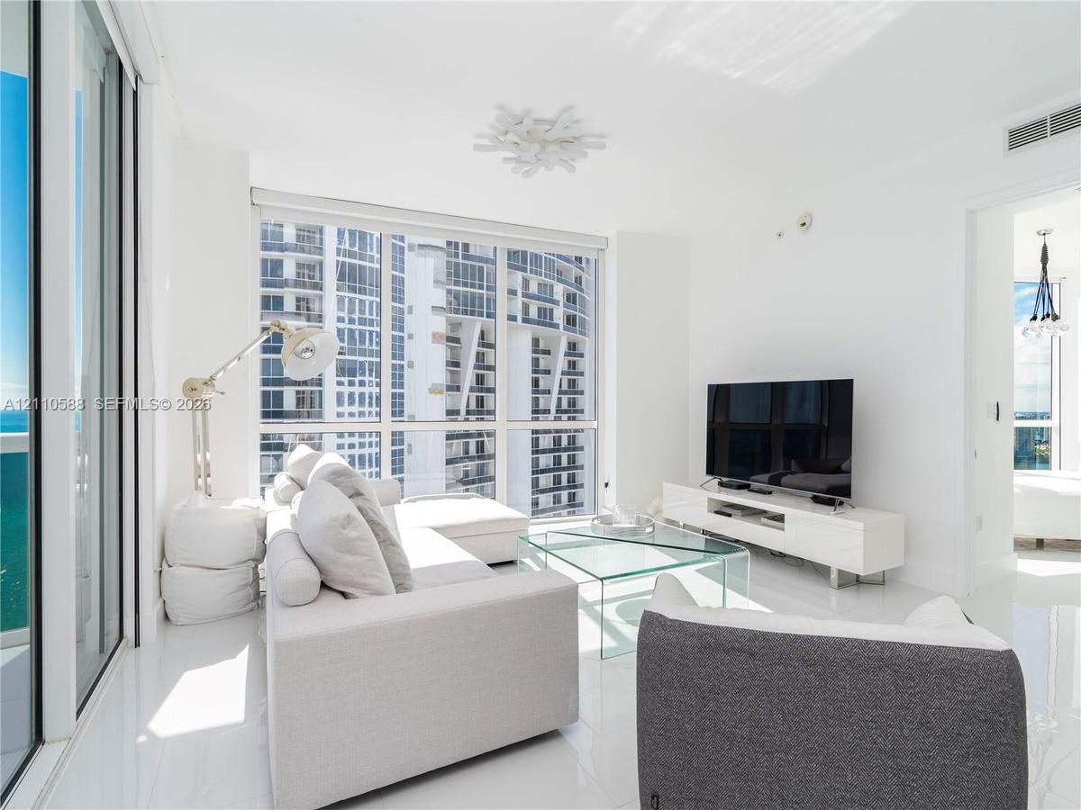 Floor-to-ceiling windows, high-gloss white flooring, white walls, and a decorative contemporary ceiling fixture