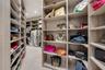 Walk-in closet featuring extensive custom wood-finish built-in cabinetry, multiple open shelving units, and integrated hanging racks