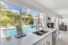 Kitchen featuring expansive windows, white cabinetry, quartz countertops, dual-basin stainless steel sink, and stainless steel dishwasher