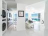 Polished tile flooring, floor-to-ceiling windows, built-in stacked laundry unit, and stainless steel kitchen appliances