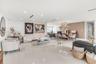 Open-concept interior featuring large-format tile flooring, recessed ceiling lighting, textured accent wall, and a contemporary multi-arm chandelier