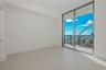 Floor-to-ceiling glass sliding doors, large-format tile flooring, and a private balcony featuring a metal railing