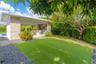 Outdoor pavilion featuring a textured stone facade, integrated built-in kitchen, low-maintenance turf lawn, and perimeter landscaping
