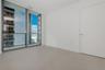 Floor-to-ceiling glass paneling, metal-framed sliding door, neutral large-format tile flooring, and integrated balcony with glass railing
