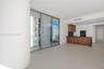 Floor-to-ceiling sliding glass doors, large-format tile flooring, kitchen featuring wood-finish cabinetry, white flat-panel upper cabinets, and dark s