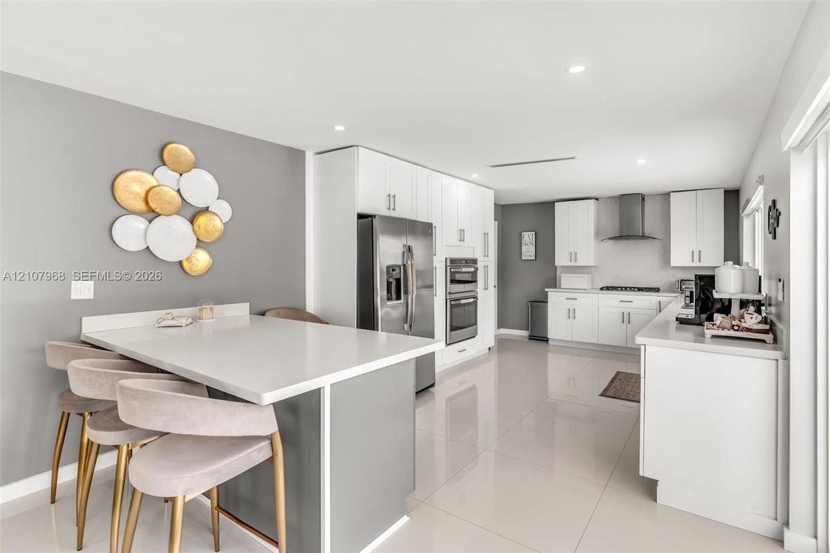Kitchen featuring white shaker-style cabinetry, quartz countertops, stainless steel appliances, recessed lighting, and large-format porcelain tile flo