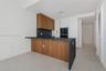 Kitchen featuring wood-finish cabinetry, dark stone-style countertops with a waterfall edge, matching full-height backsplash, stainless steel faucet, 