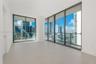 Floor-to-ceiling glass windows, expansive private balcony with glass railings, and light-toned large-format tile flooring