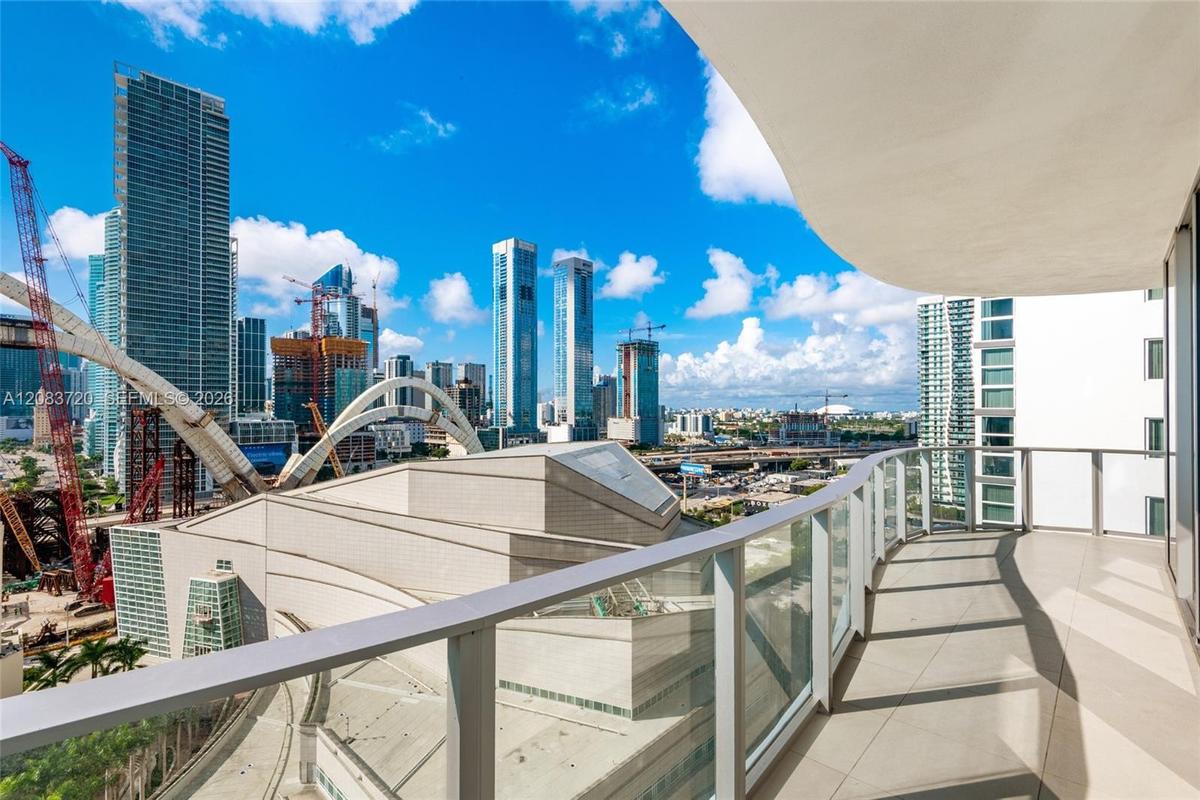 Curved exterior balcony featuring large-format tile flooring and glass panel railings