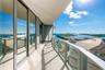 Curved exterior balcony featuring large-format tile flooring, floor-to-ceiling glass paneling, and a tempered glass railing