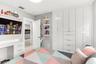 Floor-to-ceiling white cabinetry featuring integrated drawer storage, built-in white desk with drawer storage, and wall-mounted white shelving