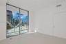 Floor-to-ceiling glass sliding doors, private balcony with metal railing, and light-toned tile flooring