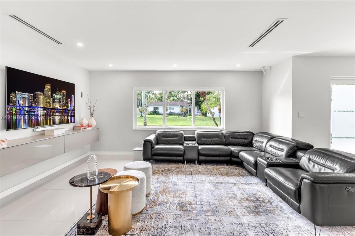 Living area featuring large-format tile flooring, recessed ceiling lighting, and a wall-mounted floating cabinetry unit