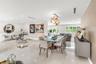 Large-format white tile flooring, modern geometric chandelier, textured feature wall, and multi-panel glass garden doors