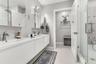 Dual-sink floating vanity with white cabinetry, integrated rectangular basins, and brushed-nickel faucets, complemented by a walk-in glass shower feat