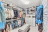 Custom walk-in closet featuring extensive white built-in shelving, integrated dresser drawers with hardware pulls, and overhead lighting