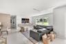 Open-concept interior featuring large-format tile flooring, a wall-mounted floating media console, recessed lighting, and expansive windows