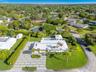 Aerial perspective featuring a metal roof, paved geometric driveway, swimming pool, detached structure, and mature landscaping