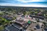 Aerial perspective of a corner commercial property featuring paved surface parking, multi-directional road access, and a flat-roof structure