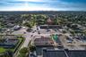 Aerial view of commercial property featuring a flat roof structure, paved surface parking area, street-front positioning, and proximity to local thoro