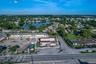 Aerial perspective of a corner commercial property featuring direct street access, a paved parking lot, and proximity to a regional waterway