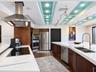 Kitchen featuring wood-veneer cabinetry, quartz countertops, a stainless steel chimney hood, built-in double ovens, and a recessed ceiling installatio