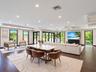 Open-concept interior featuring dark wood-finish flooring, recessed lighting, expansive glass door panels with black frames, and recessed tray ceiling