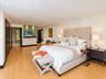 Spacious room featuring light wood-finish flooring, recessed ceiling lighting, and a frosted glass partition wall