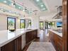 Modern kitchen featuring custom wood cabinetry, quartz countertops, a stainless steel range hood, track lighting, and recessed ceiling accents