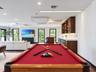 Custom built-in bar featuring wood cabinetry, stone countertops, and glass-front storage shelving