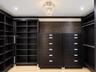 Custom dark wood-finish built-in cabinetry featuring extensive shelving, integrated drawer units with metallic hardware, and a center decorative cryst