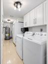 Laundry area featuring white shaker-style wall cabinets with brushed nickel hardware, polished tile flooring, and multi-light flush-mount ceiling fixt
