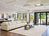 Open-concept living space featuring wood-finish flooring, custom tray ceiling with recessed lighting, and expansive floor-to-ceiling sliding glass doo