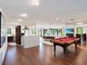 Open-concept interior featuring wood-finish flooring, recessed lighting, a stone-surfaced kitchen island, and multiple floor-to-ceiling glass panel do