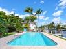 Rectangular in-ground swimming pool with integrated metal handrails, paver stone pool deck, and direct water frontage featuring a private dock