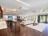 Open-concept living space featuring wood-finish flooring, custom coffered ceiling with recessed lighting, built-in bar with stone countertop, and floo