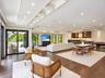 Spacious interior featuring recessed lighting, tiered tray ceilings, wood-finish flooring, and a built-in wet bar with cabinetry