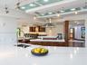 Custom kitchen featuring wood-finish cabinetry, white stone countertops, stainless steel range hood, glass-panel ceiling accents, and adjustable track