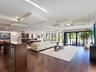 Open-concept interior featuring wood-finish flooring, custom geometric drop-ceiling detailing, recessed lighting, and expansive multi-panel sliding gl