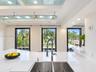 Kitchen featuring a white stone-finish countertop, dual-basin stainless steel sink with a high-arch gooseneck faucet, ceiling-mounted track lighting w