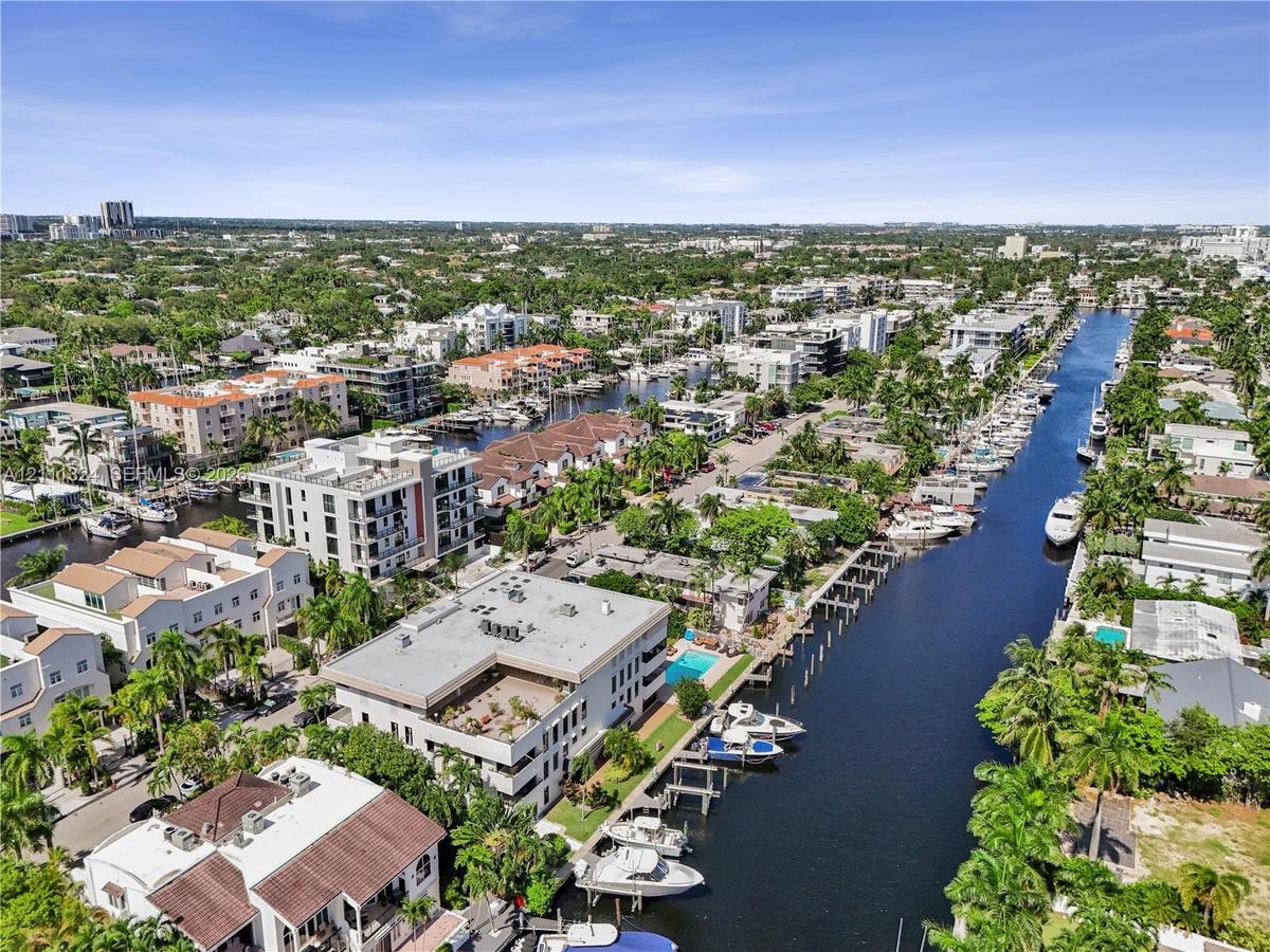 Aerial perspective of a waterfront residential district featuring private boat slips, deep-water canal access, multi-story masonry structures, and lus