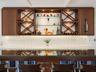 Custom built-in bar featuring wood cabinetry, integrated glass shelving, cross-hatch wine storage, under-cabinet lighting, and a white countertop