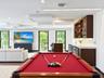 Custom wet bar featuring dark wood cabinetry, white stone countertops, under-cabinet lighting, and built-in wine storage