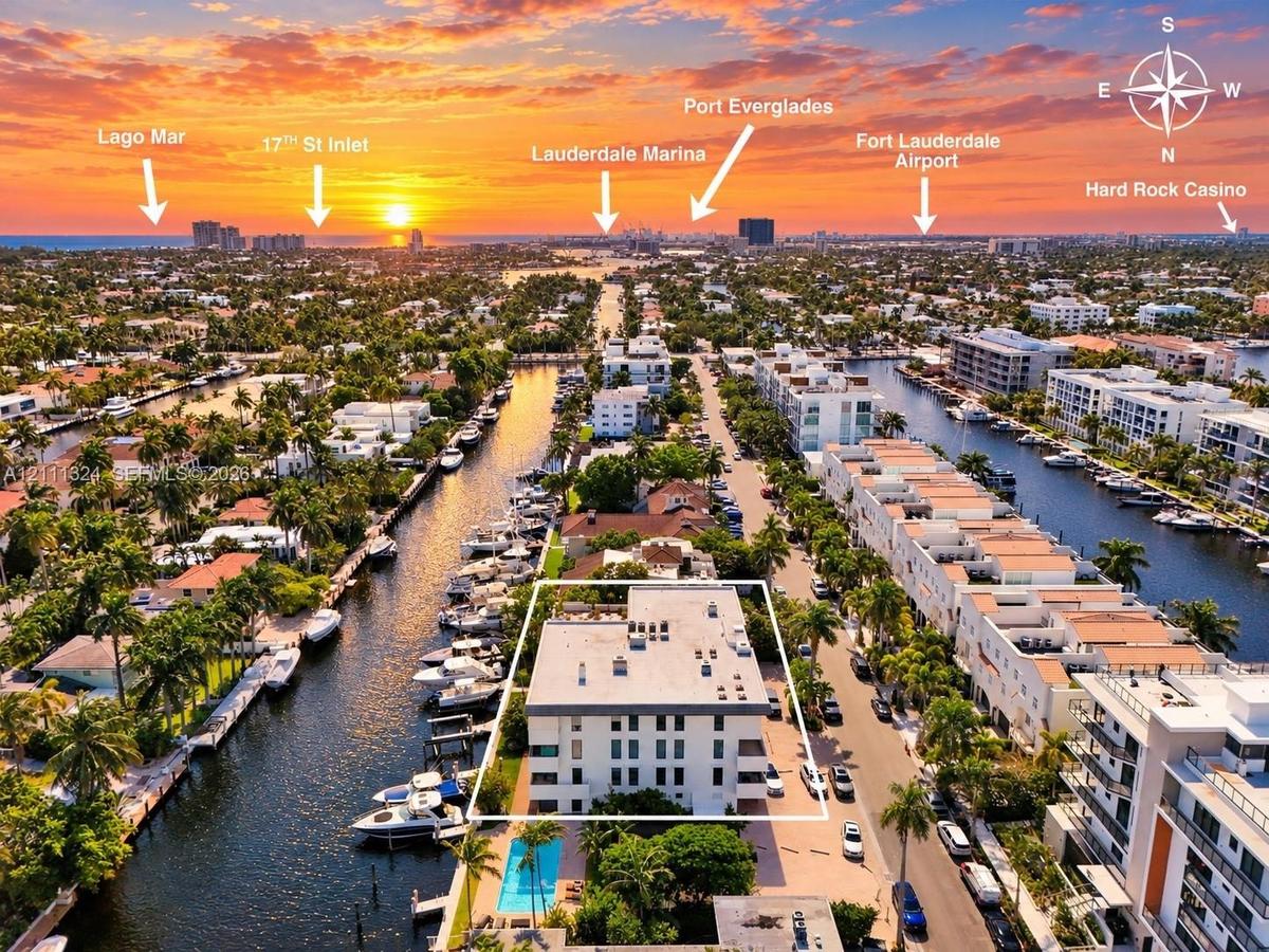 Aerial perspective featuring multi-story residential building, private swimming pool, deep-water canal access, and mature landscaping