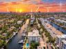 Aerial perspective featuring multi-story residential building, private swimming pool, deep-water canal access, and mature landscaping