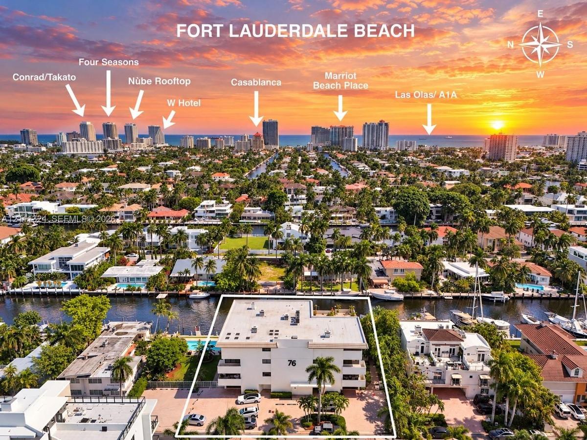 Aerial perspective of property featuring deep-water canal frontage, paved surface parking, and mature palm trees